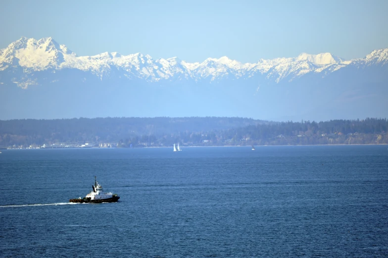 a small boat speeding through the water in front of mountains