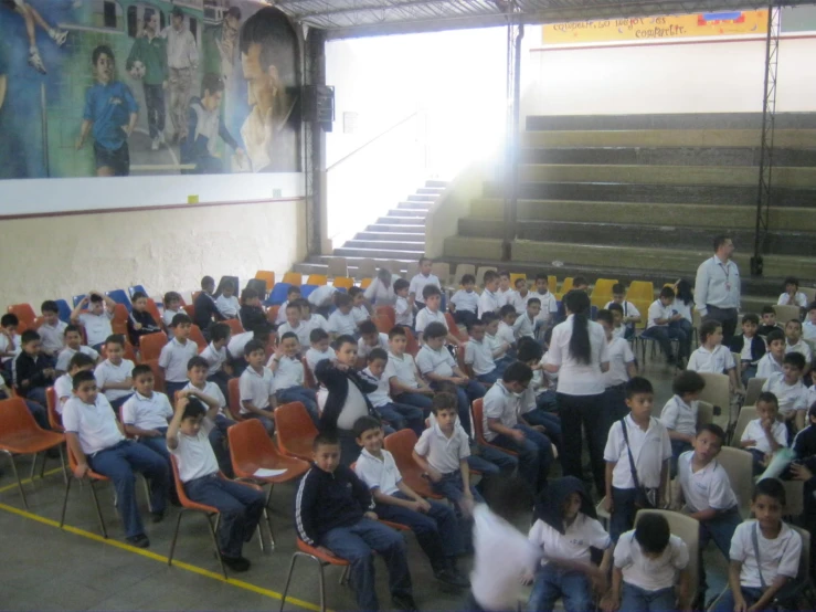 there are some children sitting in a large group in a building