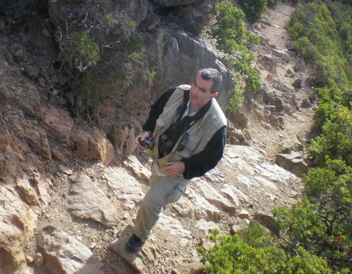 man in black vest and hat carrying a camera down a hill