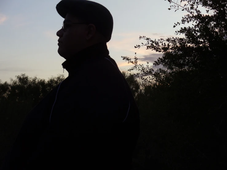 a man standing in a forest near trees and grass