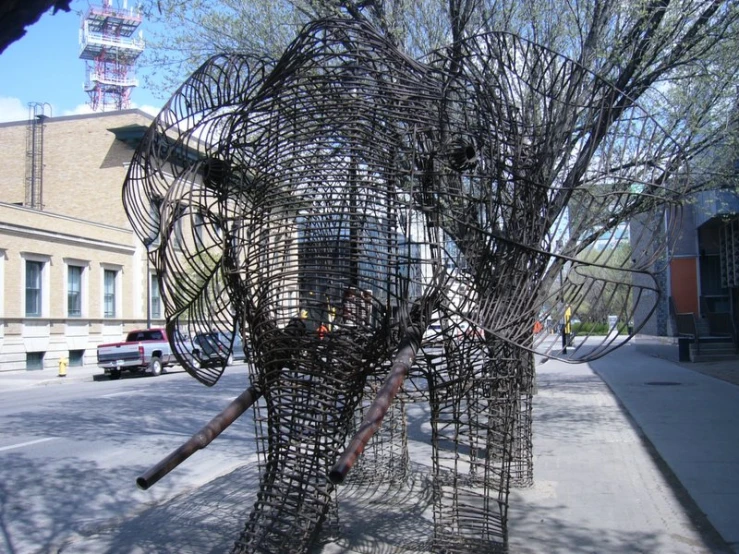 an intricate wire elephant sculpture next to a city street
