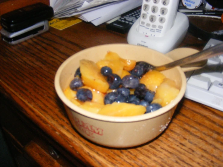 blueberries and peaches are served in a bowl with a spoon