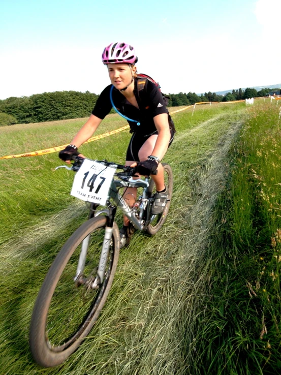 the woman rides her bike through a grassy field