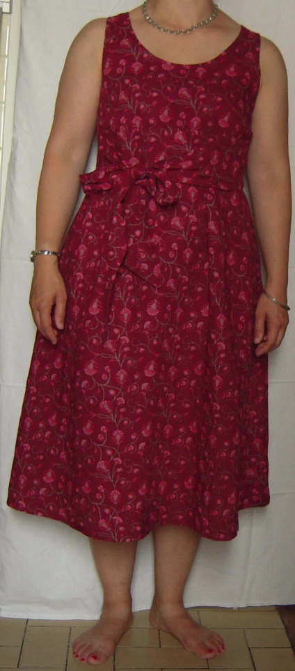 a woman in red floral dress standing next to a white backdrop