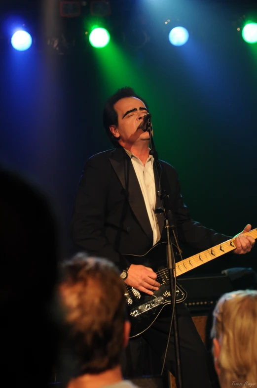 a man playing a guitar and singing into microphones