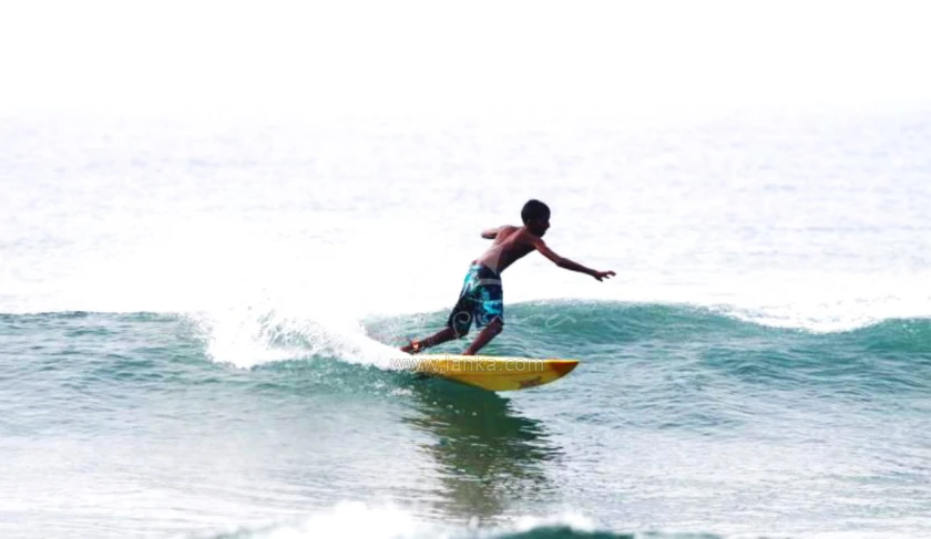 a young man riding on top of a wave on a yellow surfboard