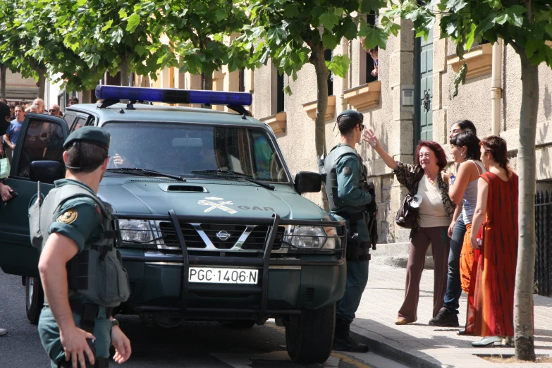 police in uniforms stand outside a van and women stand on a sidewalk