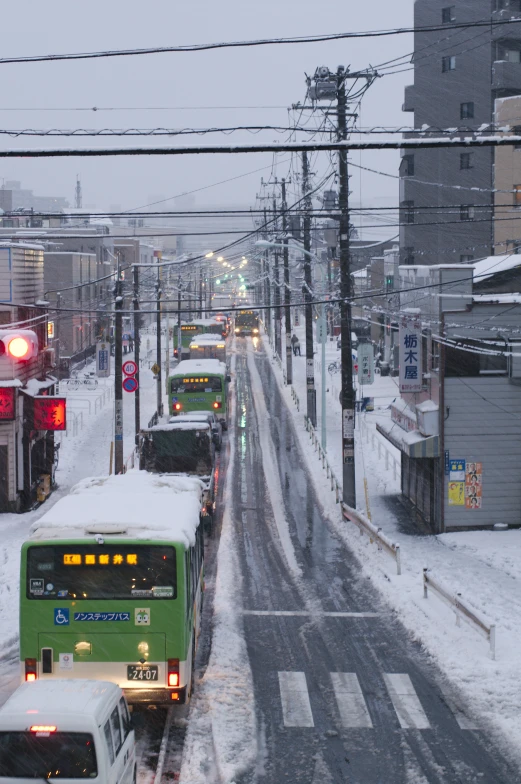a snow - covered street with buses and cars stopped at a stoplight