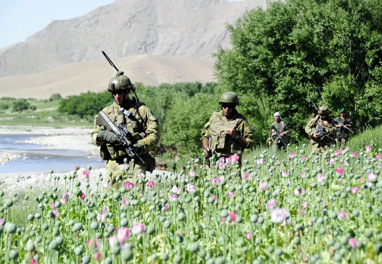 the soldiers are walking across the field with their guns