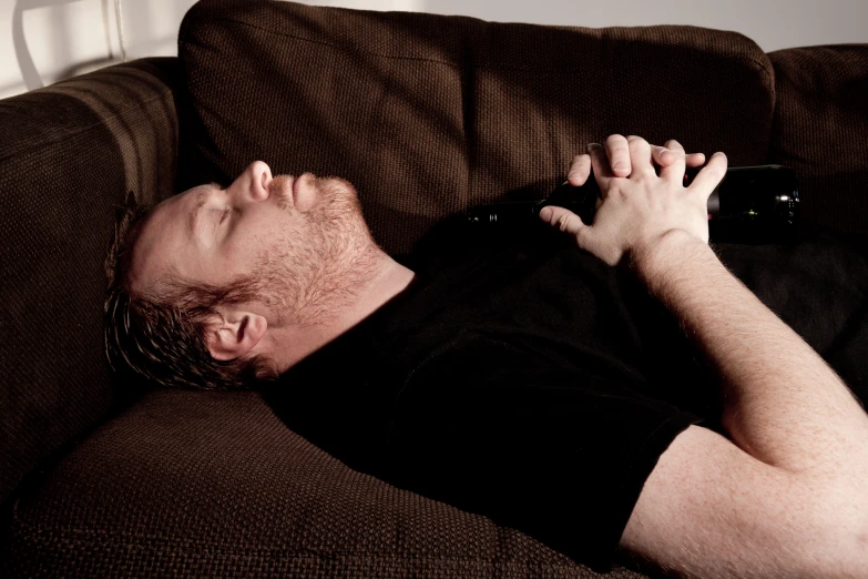 a man with his eyes closed lays on the couch