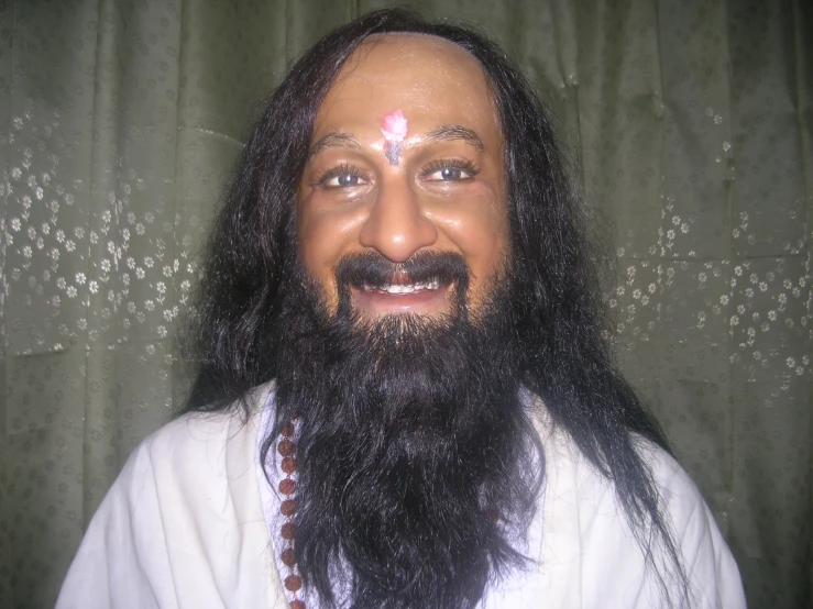 a man with beard wearing white shirt next to curtains