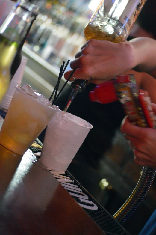 drinks being poured into several plastic cups