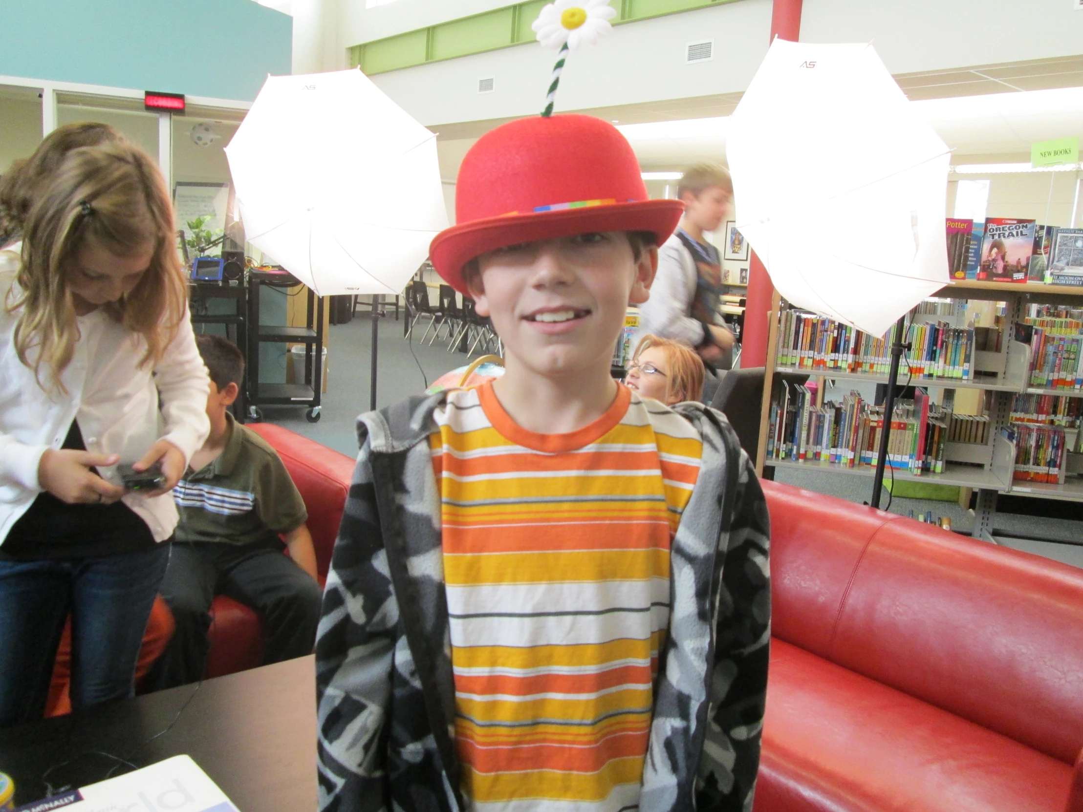 a boy wearing a red hat with an umbrella on it