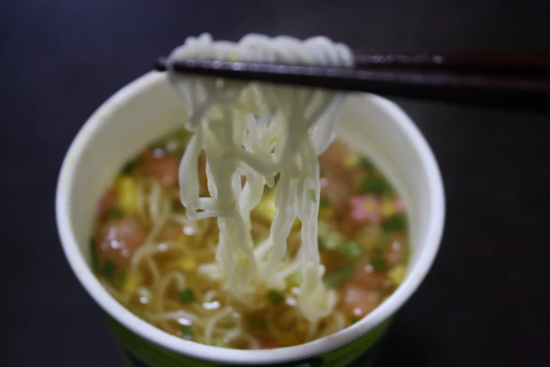 a close up of a bowl of soup with chop sticks