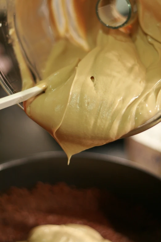 a spoon drizzing melted cheese into a pot