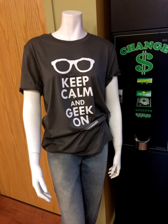 a black t - shirt with glasses printed on it sits next to a vending machine