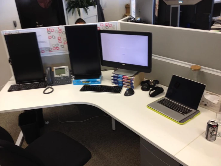 two computer monitors and a laptop sit on an office desk