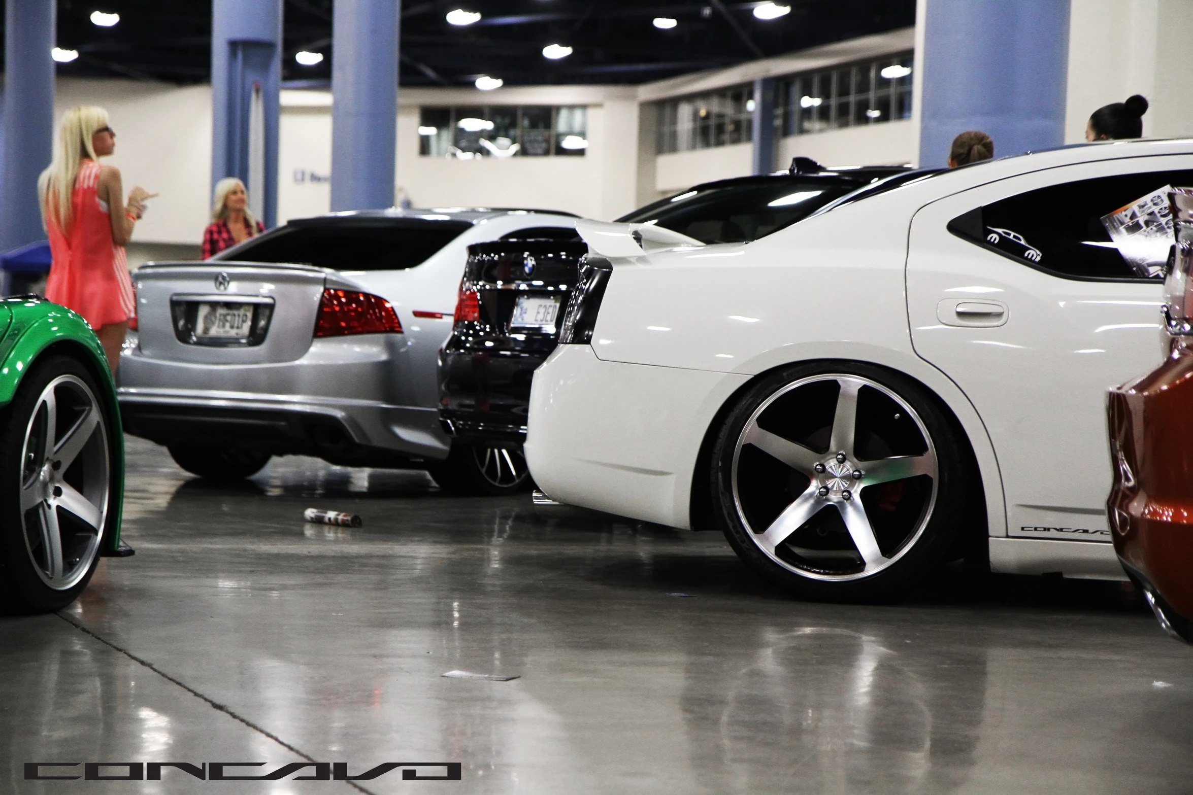 several cars in a show room, one in silver and one green