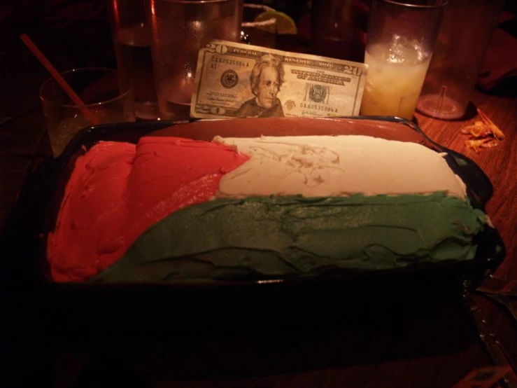 a money bill on top of a green red and white cake