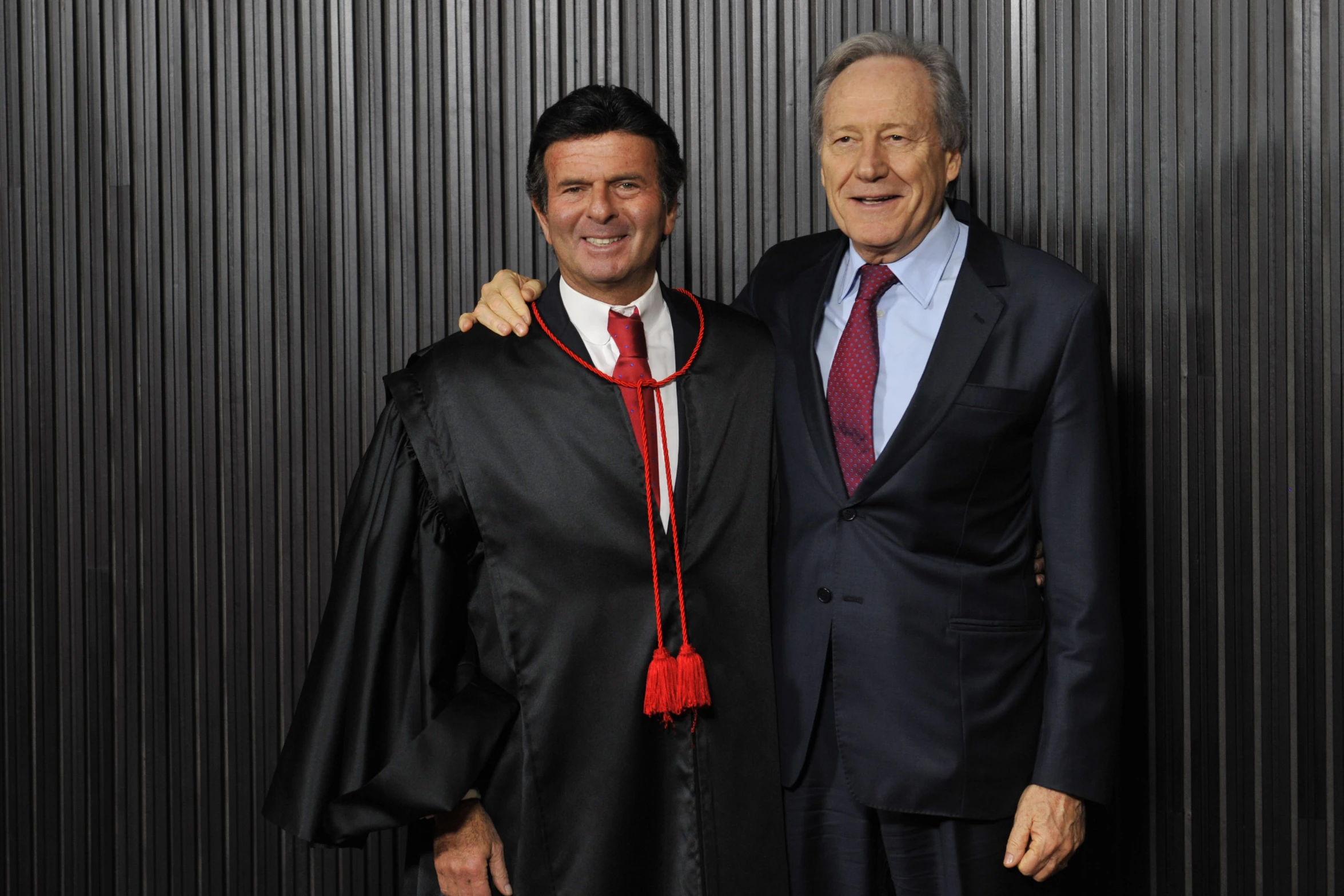 two men wearing suits and tie stand next to each other