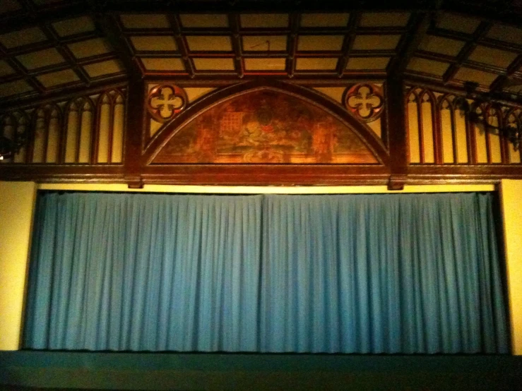 an elaborately designed auditorium has a blue curtain