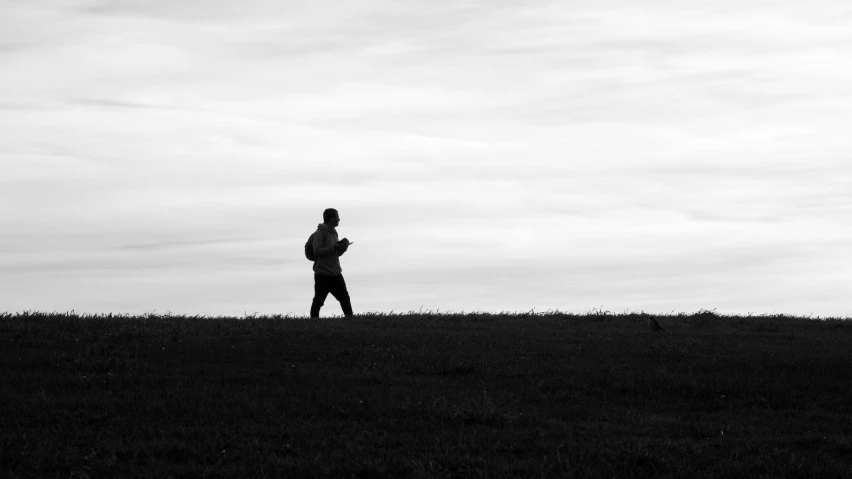 a man standing in the grass holding onto his jacket