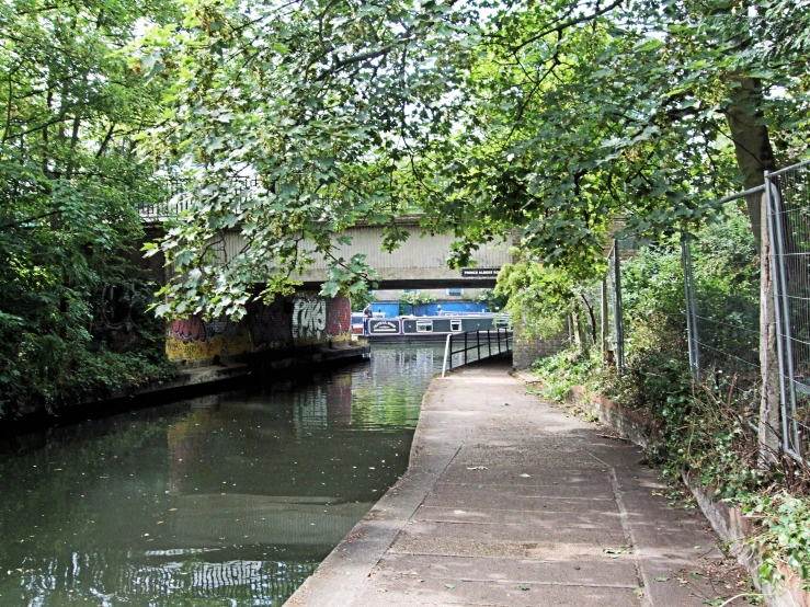 a trail next to a river under a bridge