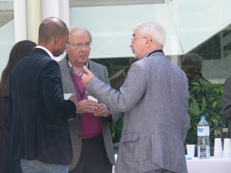 three men standing next to each other in front of a building