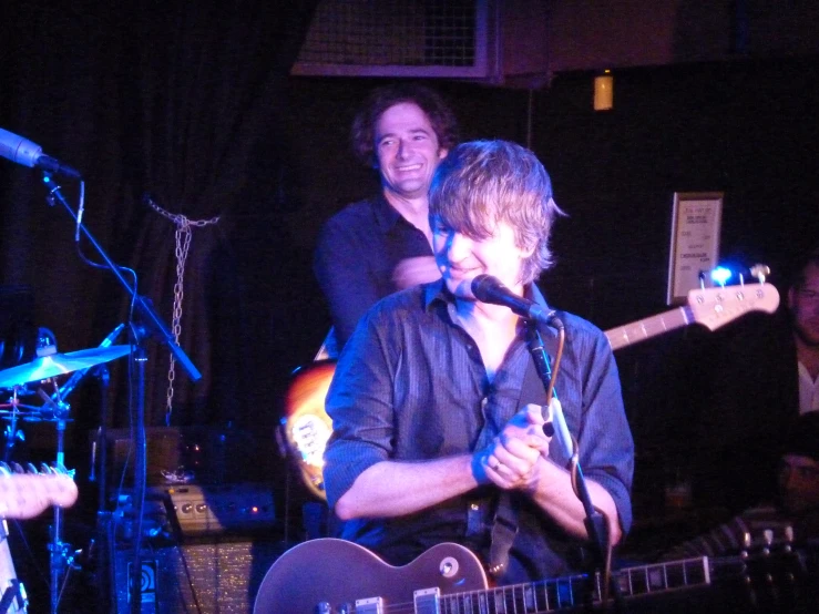 three men standing around and singing into microphones