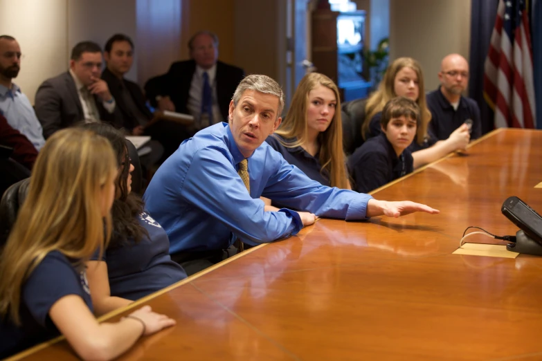 a man sitting at a large table with other people around him