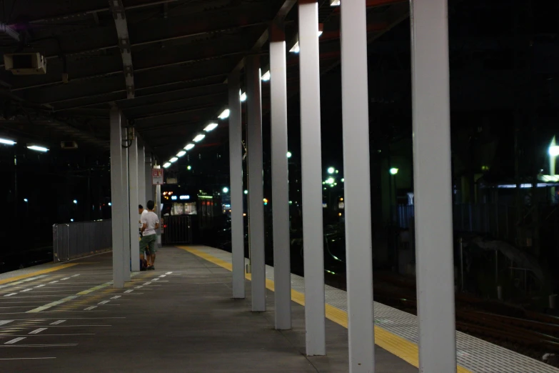 an empty train station at night with a man walking by