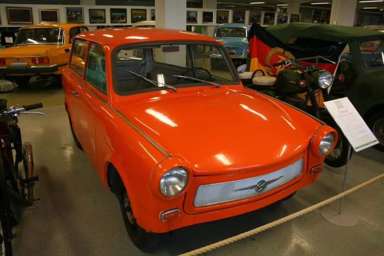 an orange car sitting in a museum next to other old cars