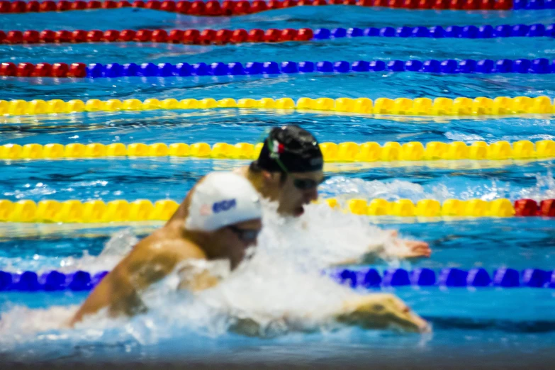 a group of swimmers swimming and jumping in an indoor swimming pool