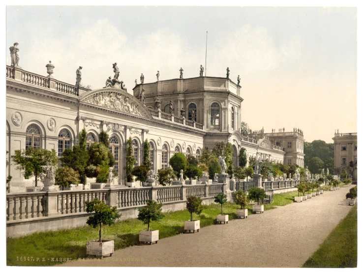 a building with pillars and balcony that sits in front of a garden