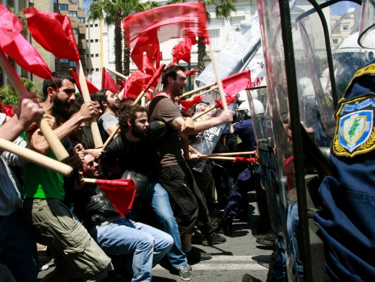 a group of people sitting down holding flags and signs