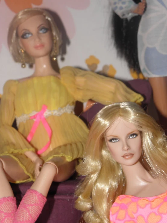 two barbie dolls are sitting on top of a couch