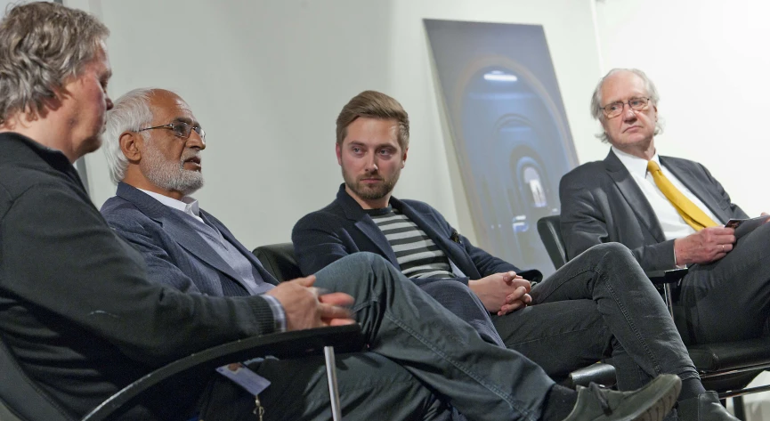 four men are sitting in chairs in a room