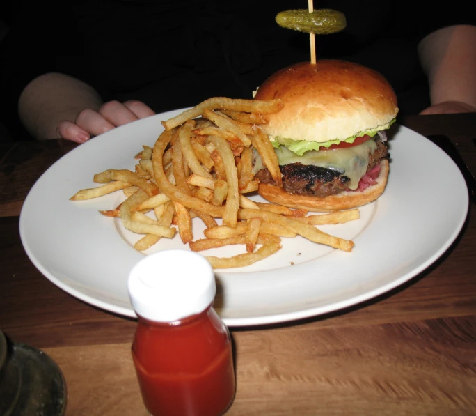 a large hamburger and french fries on a white plate