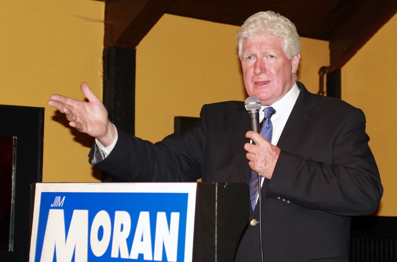 a man holding a microphone standing next to a sign