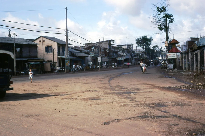 an old fashioned road with people and children riding motorcycles