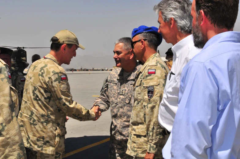 military men shake hands next to each other