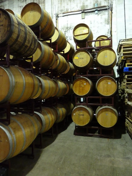 the wine barrels in the cellar are stacked high up