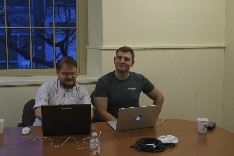 two men at a table working on laptops