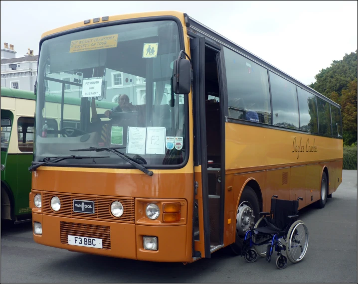 an orange bus is parked near a yellow bus