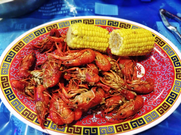 the crawfish is in a bowl next to a corn on the cob