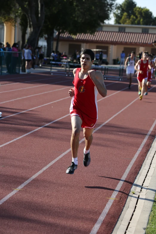 a boy in a red shirt and black shorts running on a track