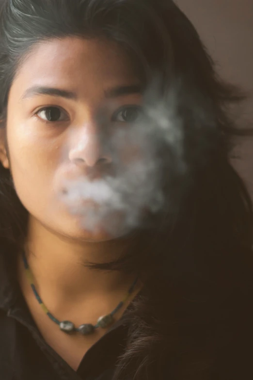 a woman is smoking a cigarette outside with a necklace