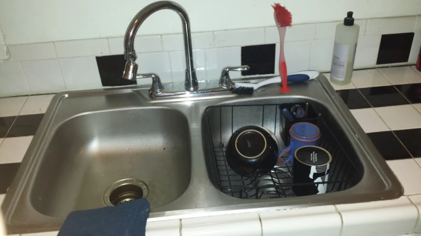 there are many kitchen items in the metal sink