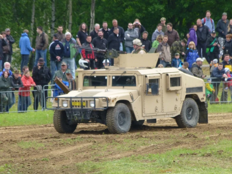a military vehicle on a dirty field near a crowd