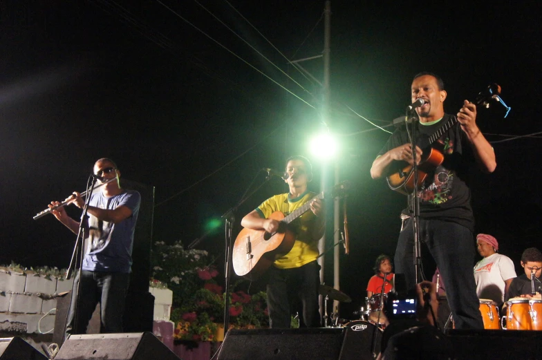 the man is playing guitar in front of other musicians